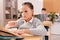 Pensive and frowning schoolgirl looking at task in book and thinking of answer