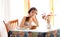 Pensive girl with book sitting at table indoor