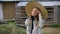 Pensive girl in straw hat and dress looking aside on farmland