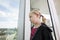 Pensive girl in vampire costume looking out through window at home