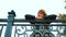 Pensive girl wearing beret and coat posing on metal bridge