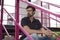 Pensive handsome guy sitting on stairs wearing glasses look to the left. City view buildings behind