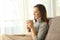 Pensive lady holding a cup of coffee at home in winter