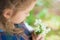 Pensive little girl holding a bouquet of chamomile in the spring