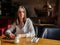 Pensive lonely woman is sitting at the table in a restaurant and looking to the window