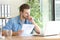 Pensive man holding document reading laptop content