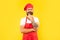 Pensive man in red toque and apron stroking chin yellow background, chef