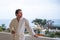 A pensive man in a white bathrobe is standing on the balcony with a beautiful view of the sea