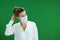 Pensive modern female teacher in blouse against green with mask