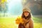 Pensive modern woman with yellow leaves outside in autumn park