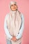 Pensive muslim girl in hijab, isolated on pink