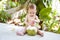 Pensive and passionate infant baby at tropical vacation. Eats and drinks green young coconut with spoon