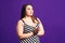 Pensive plus size model in striped dress, fat woman on purple background
