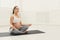 Pensive pregnant woman training yoga in lotus pose