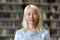 Pensive pretty Asian blonde student girl posing in university library