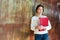 Pensive pretty young woman holding red ring binder folder