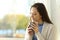 Pensive relaxed woman drinking coffee at home