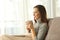 Pensive relaxed woman holding coffee at home