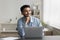 Pensive satisfied Indian man sitting at desk with laptop