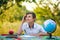 Pensive schoolboy pupil studying at a table in a garden outdoors