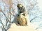 A pensive statue sitting on top of a headstone.