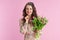 pensive stylish woman with long wavy brunette hair on pink