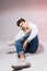 Pensive teen boy posing sitting on the floor in the studio. Portrait of stylishly dressed student. Studio shot Handsome attractive