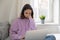 Pensive teen girl in headphones using laptop at home