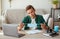 Pensive teen guy holding protective mask, studying at home