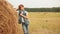 Pensive teenage boy leaning at haystack in field