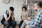 Pensive teenager sits next to his mother during a meeting with therapists for children with problems