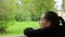 Pensive thoughtful girl meditates on the background of green trees and grass