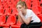 Pensive woman cheerleader sitting on the stadium podium armchair