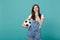 Pensive woman football fan support favorite team with soccer ball put hand prop up on chin isolated on blue turquoise