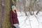 Pensive woman leaning against tree in winter