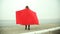 Pensive woman in red blanket looking at the sea