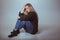 Pensive woman in sweater sitting on floor