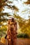 Pensive woman with yellow leaves walking outside in autumn park