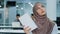 Pensive young Arabic female worker in hijab sitting at office desk using paper notebook making notes create new idea