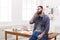 Pensive young businessman talking on mobile phone sits on the table