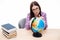 Pensive young female student sitting with globe
