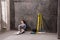 Pensive young laborer sitting on floor and looking away
