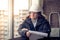 Pensive young man builder in hard hat standng and thinking. Soft focus, toned.