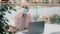 Pensive young muslim woman in medical mask in public place sitting typing on laptop arab girl in hijab writer journalist