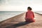 Pensive young woman tourist enjoy her life sitting on pier beach with infinity view copy space