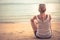 Pensive young woman tourist sitting on beach and looking into the distance