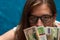 Pensive young woman wearing eyeglasses with money