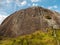 People abseiling a steep rock mountain wall in Brazil