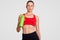 People, active lifestyle concept. Fatigue sportswoman feels thirsty after morning workout, holds green bottle with water, dressed