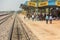 People and animals waiting for a train at a station in India.